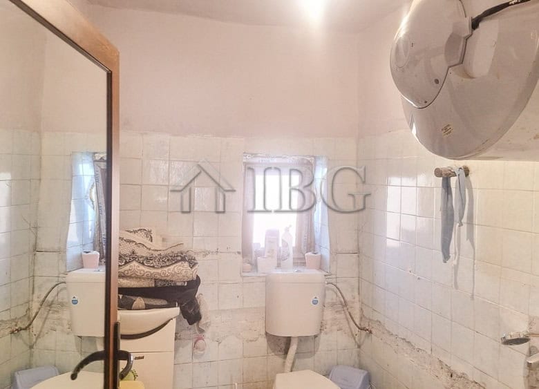 Small bathroom with white tiles, mirror, and washing area in a quiet residential setting.
