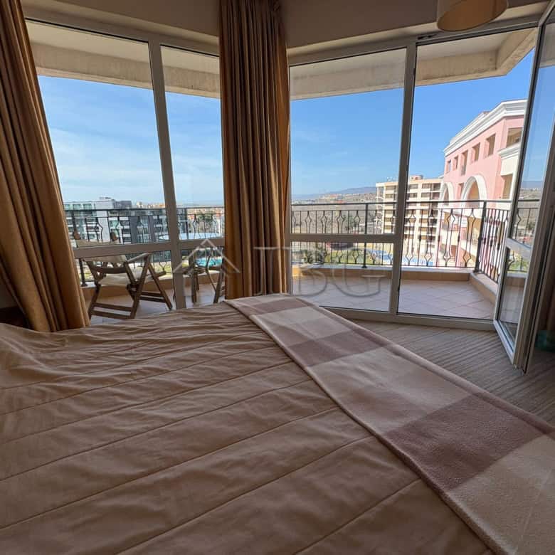 Bright bedroom with balcony overlooking Sunny Beach skyline and sea view.