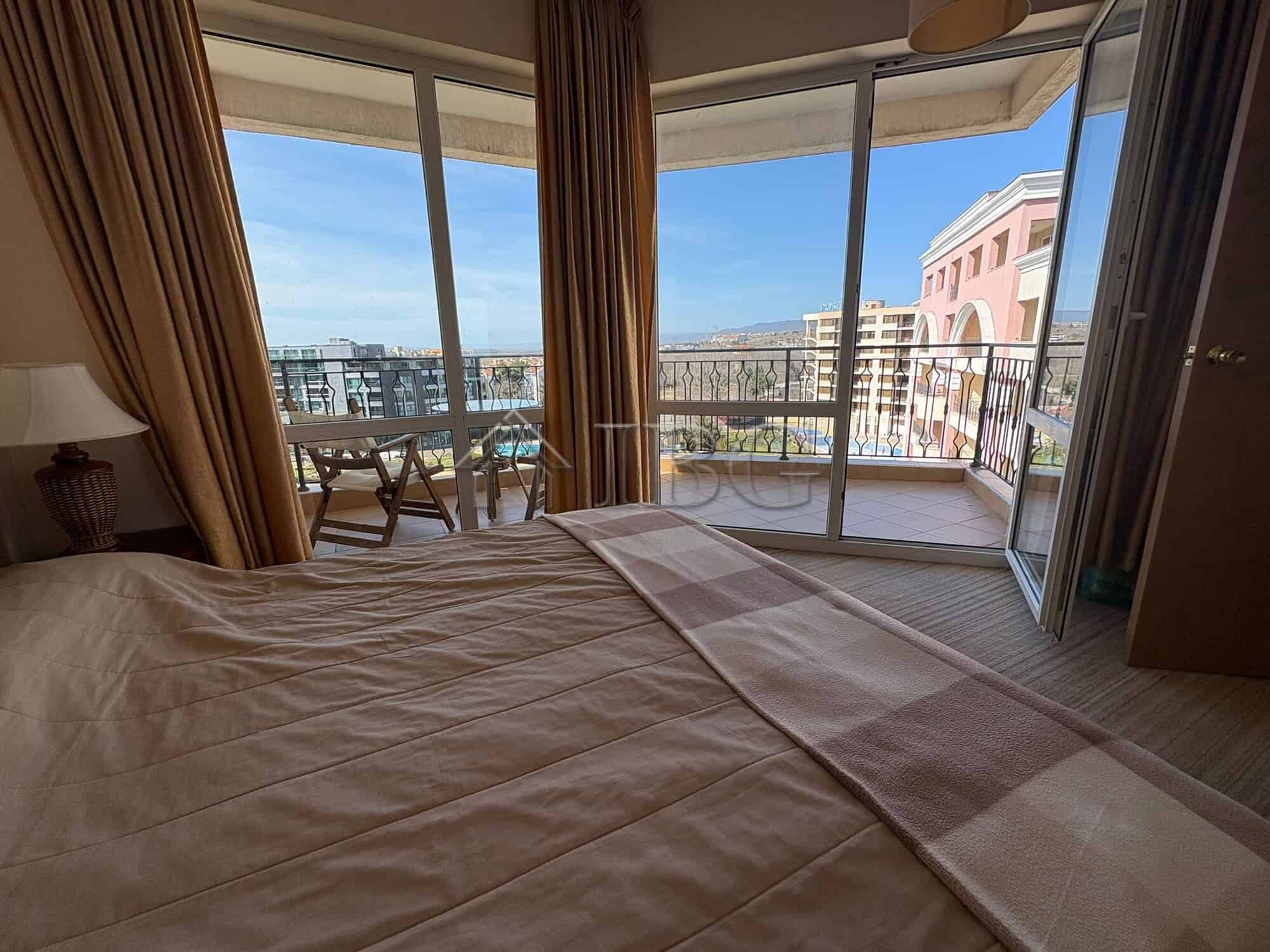 Bright bedroom with balcony overlooking Sunny Beach skyline and sea view.