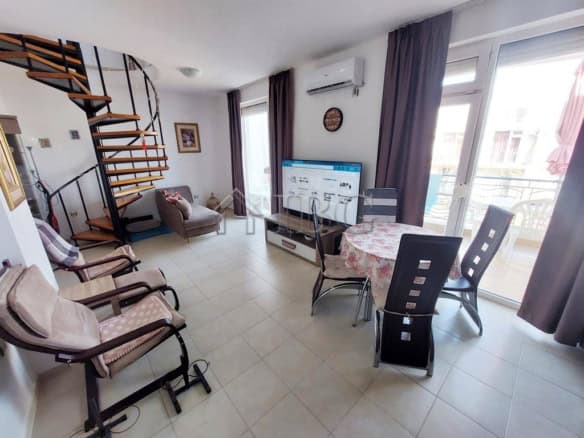 Spacious living area featuring a spiral staircase, sofa, dining table, and large windows with balcon.