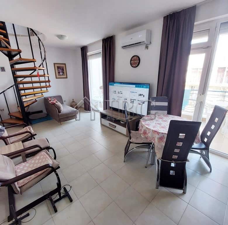 Spacious living area featuring a spiral staircase, sofa, dining table, and large windows with balcon.
