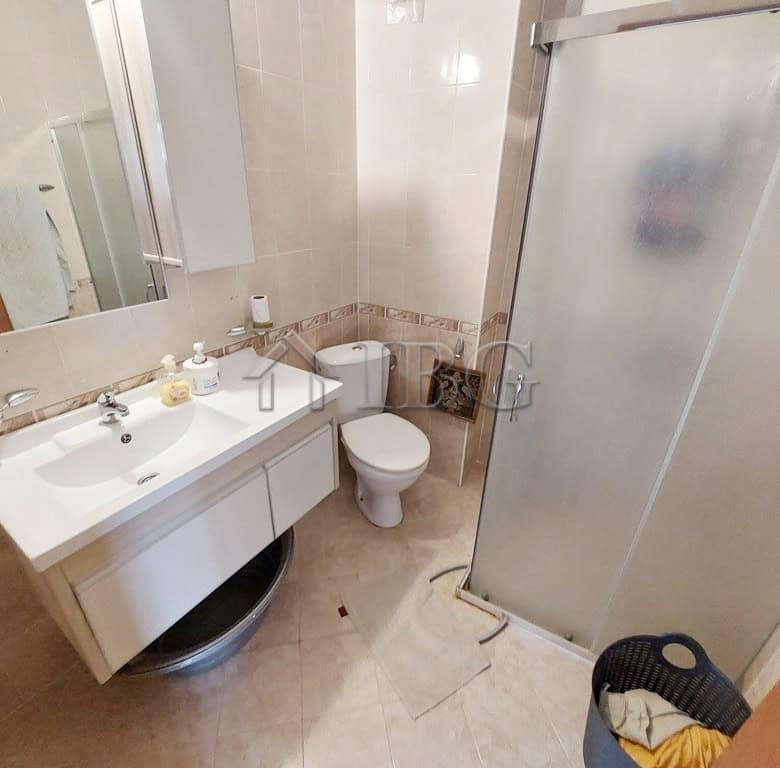 Bathroom with sink, toilet, and shower cabin in a compact apartment.
