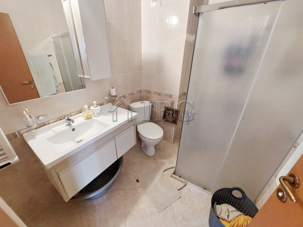Bathroom with sink, toilet, and shower cabin in a compact apartment.