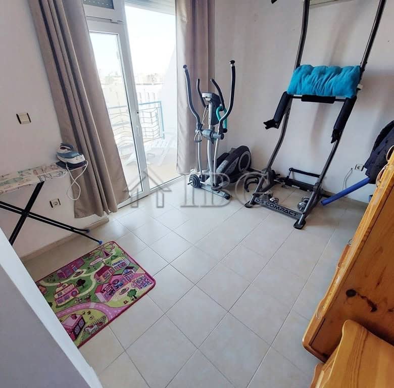Home gym with exercise equipment in a sunny apartment room.