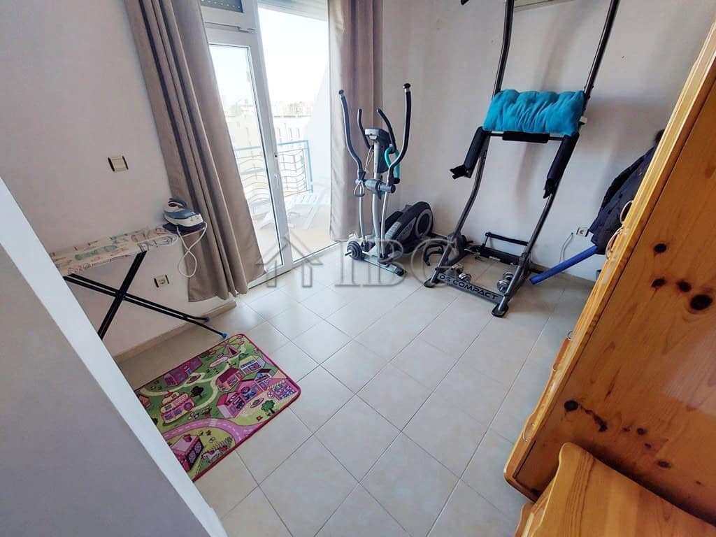 Home gym with exercise equipment in a sunny apartment room.