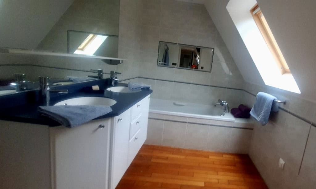 Luxury 4 Bed Le Manoir House Bright bathroom with bathtub and skylight window.