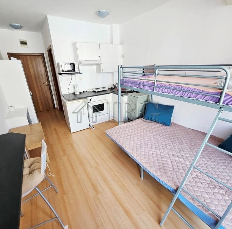 Bright studio apartment with a balcony overlooking the pool area. Compact living space with modern f.