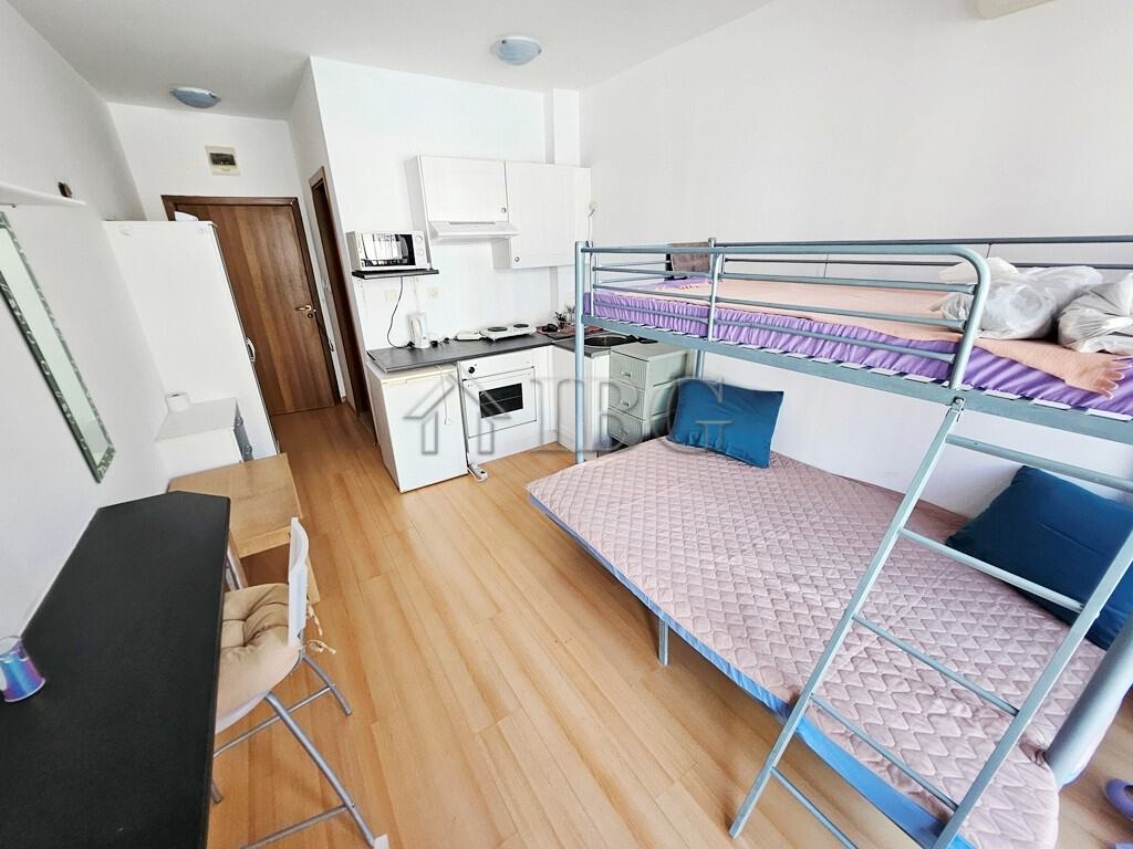 Bright studio apartment with a balcony overlooking the pool area. Compact living space with modern f.