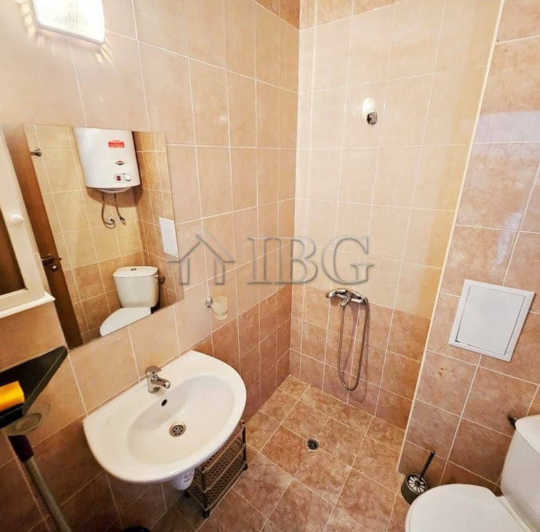 Compact bathroom with shower, sink, and toilet in a sunny studio apartment.