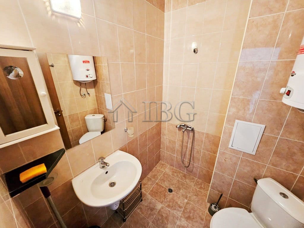 Compact bathroom with shower, sink, and toilet in a sunny studio apartment.
