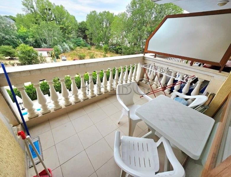 Balcony overlooking lush green garden with outdoor furniture and sunshade. Perfect for relaxing and.