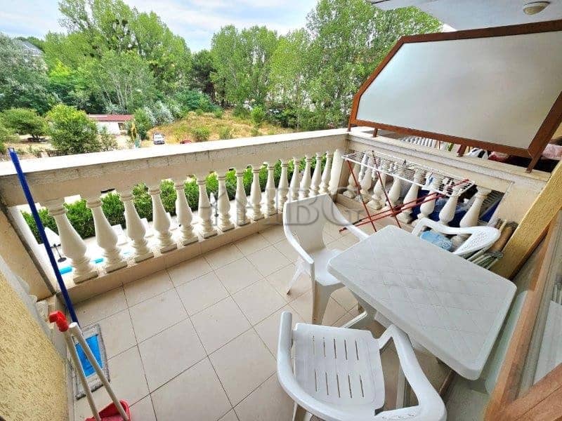 Balcony overlooking lush green garden with outdoor furniture and sunshade. Perfect for relaxing and.