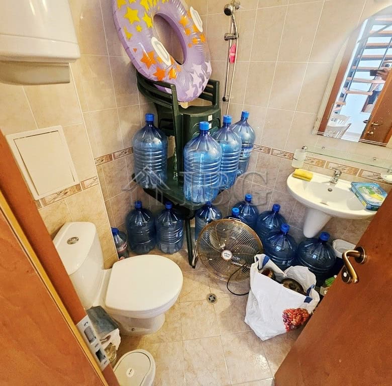 Bright bathroom with multiple water bottles and a small sink in Sunny Day 3 complex.