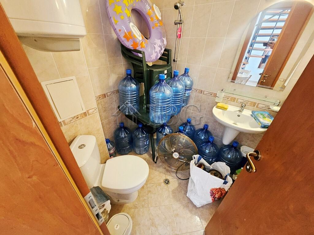 Bright bathroom with multiple water bottles and a small sink in Sunny Day 3 complex.