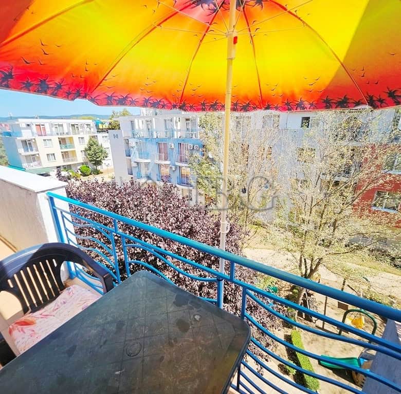 Bright balcony view of Sunny Day 3 complex with umbrella and seating.