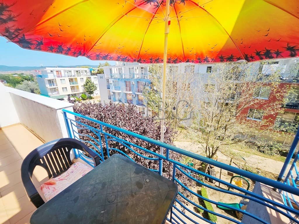 Bright balcony view of Sunny Day 3 complex with umbrella and seating.