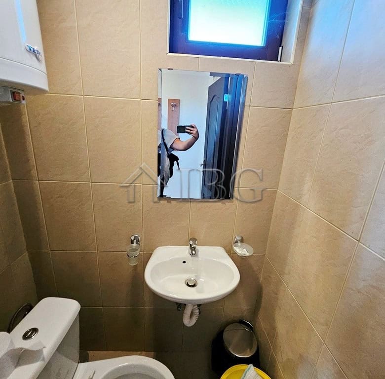 Small bathroom with sink, mirror, and toilet in Sunny Beach apartment.