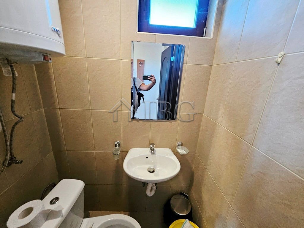 Small bathroom with sink, mirror, and toilet in Sunny Beach apartment.