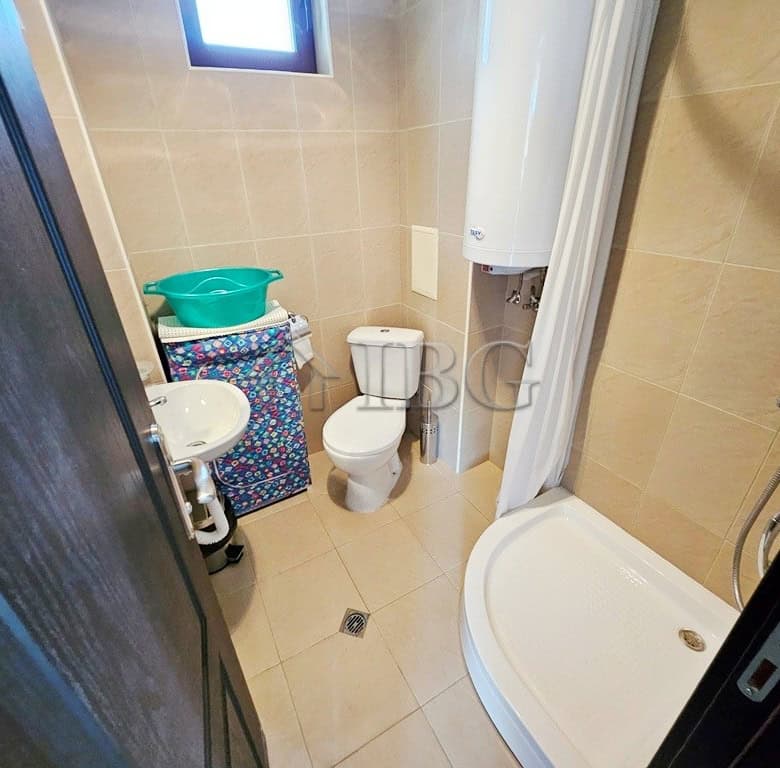 Bathroom with shower, toilet, and water heater in a sunny beach apartment.