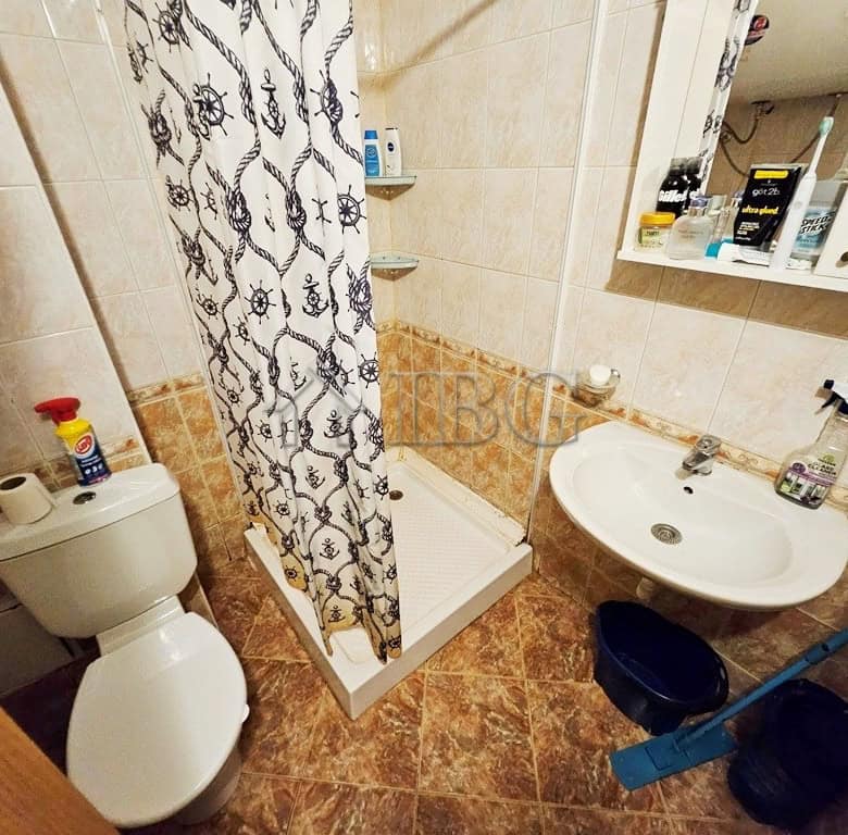 Bright bathroom with toilet, sink, and shower area in a sunny beach apartment.