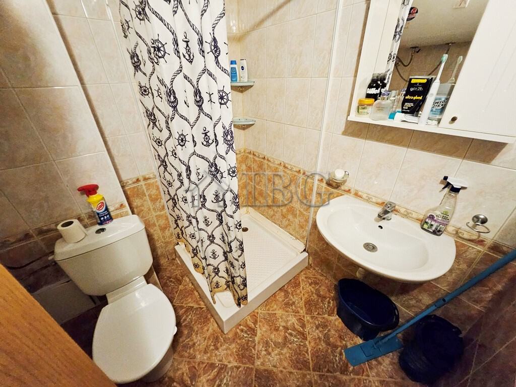 Bright bathroom with toilet, sink, and shower area in a sunny beach apartment.