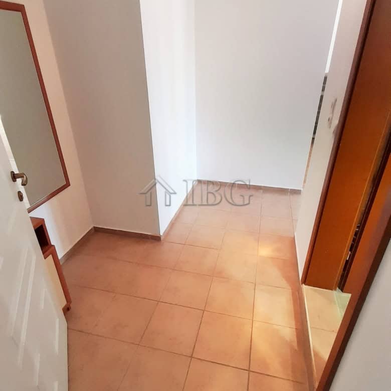 Interior view of a small apartment entrance with tiled floor and white walls.