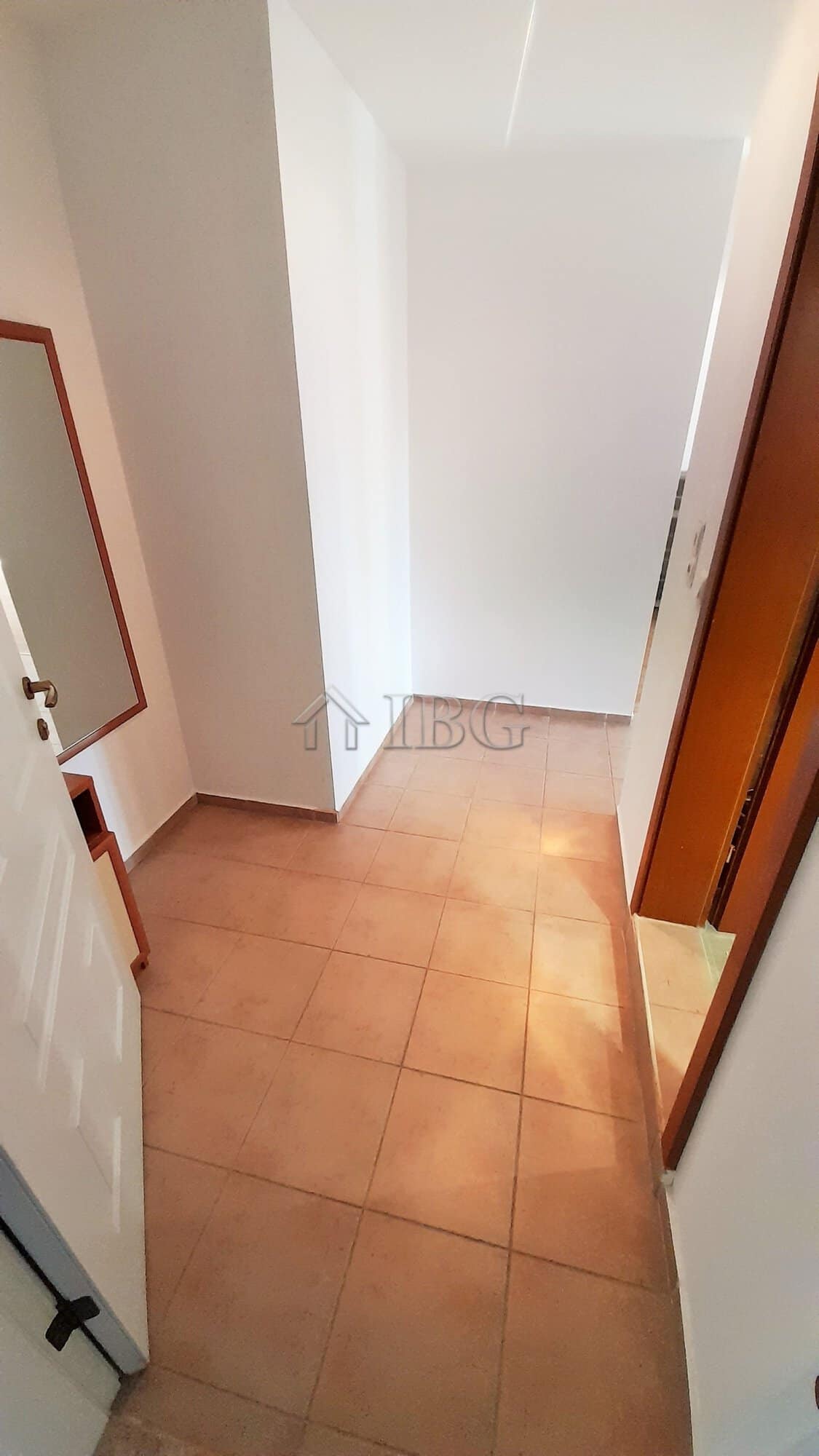 Interior view of a small apartment entrance with tiled floor and white walls.