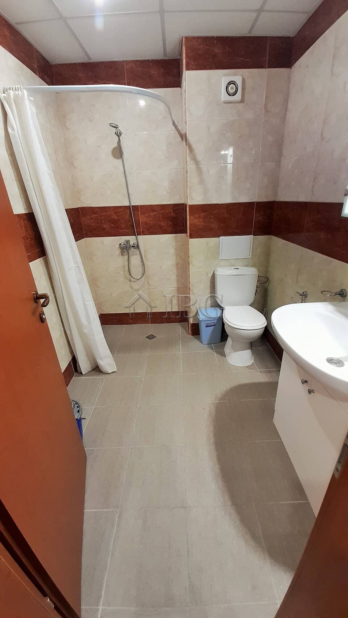 Bathroom with shower, toilet, and sink in a small apartment near the sea.