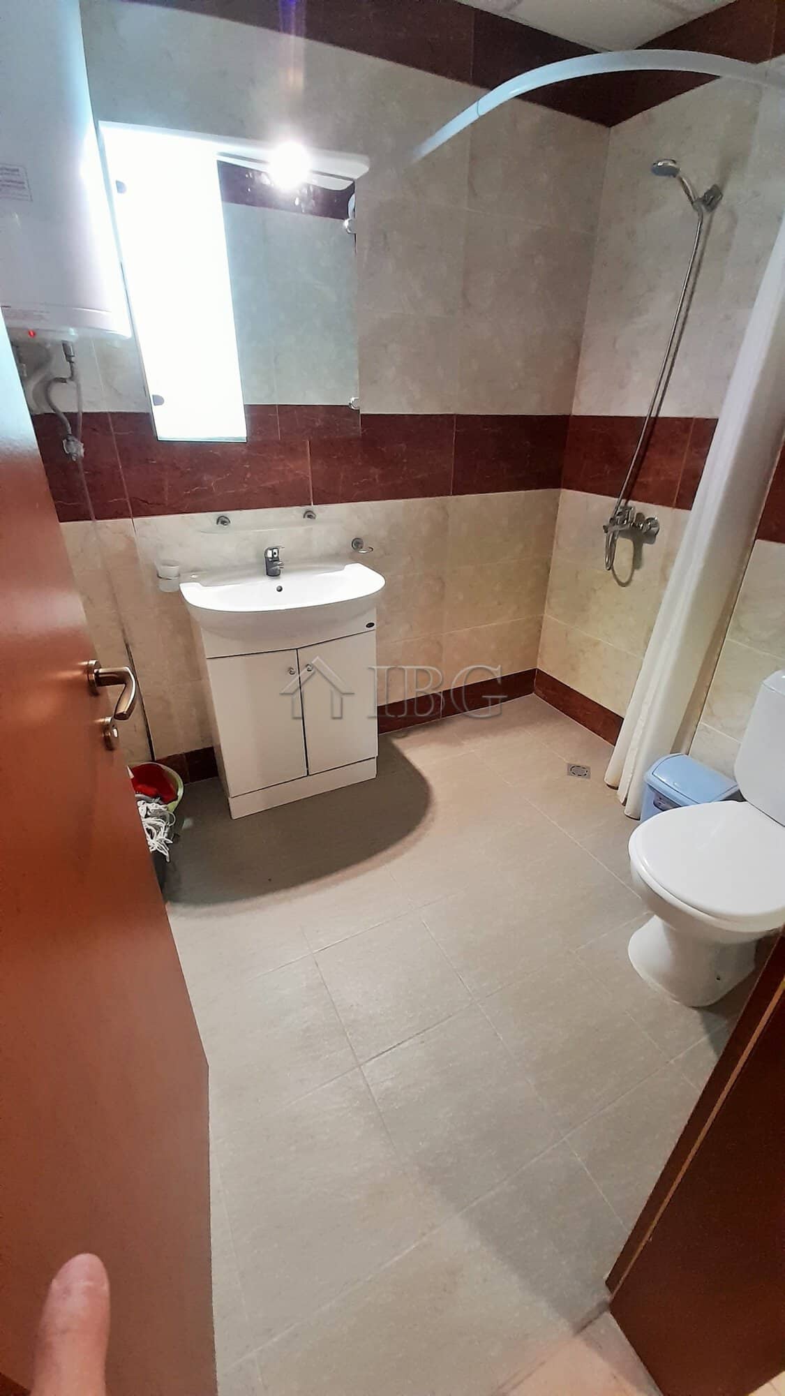 Modern bathroom in a one-bedroom apartment with shower, sink, and toilet.