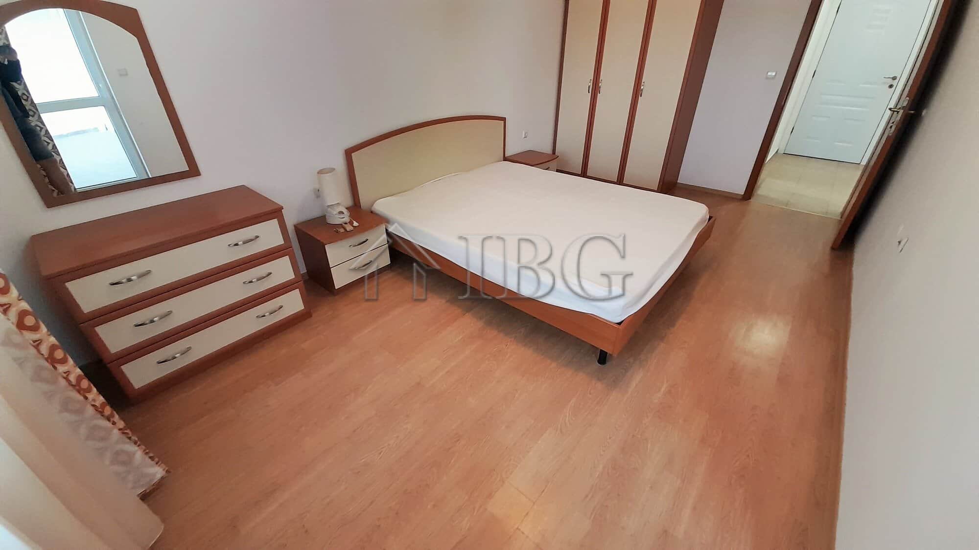 Comfortable bedroom featuring a double bed, wooden dresser, and ample natural light from a nearby wi.