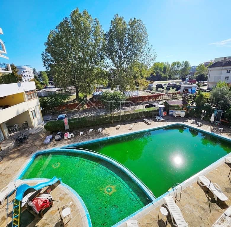 Bright view of the pool at Blue Summer Complex with lush trees and surrounding apartments.