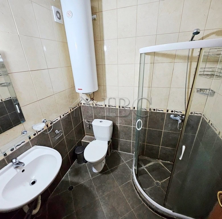 Bathroom with shower cabin, toilet, and sink in a compact, modern apartment.
