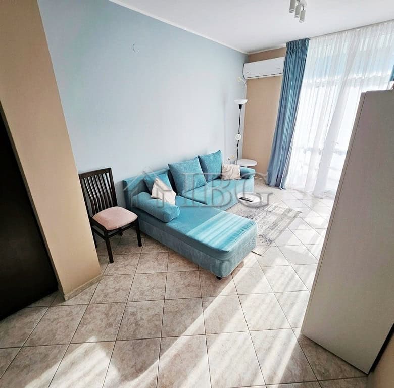 Bright living room with blue sofa and large windows in Pirop City, Sunny Beach.