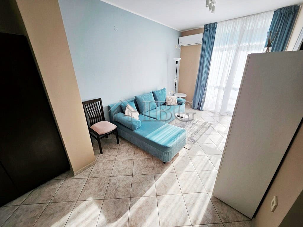 Cozy 2-Room Apartment in Sunny Beach Bright living room with blue sofa and large windows in Pirop City, Sunny Beach.