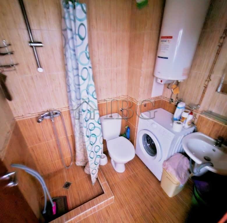 Bathroom with washing machine, shower, and toilet in a compact apartment.