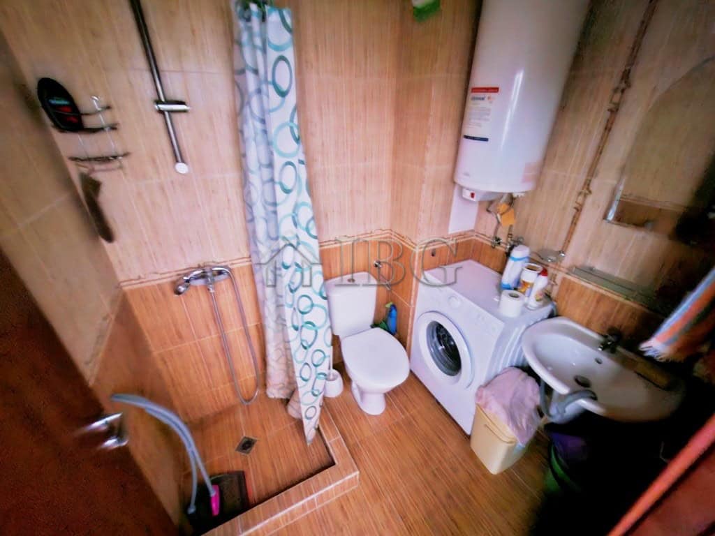 Bathroom with washing machine, shower, and toilet in a compact apartment.