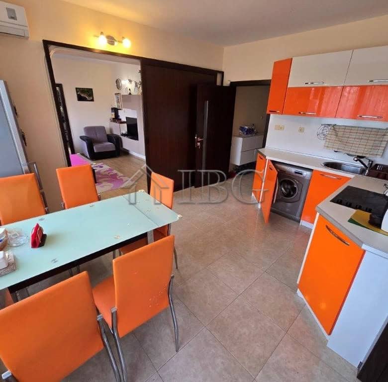 Spacious kitchen and dining area with vibrant orange cabinets and seating for six.