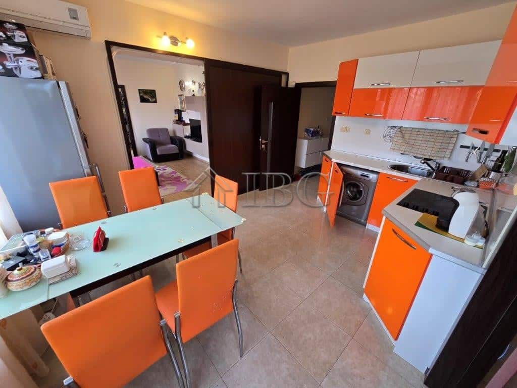 Spacious kitchen and dining area with vibrant orange cabinets and seating for six.