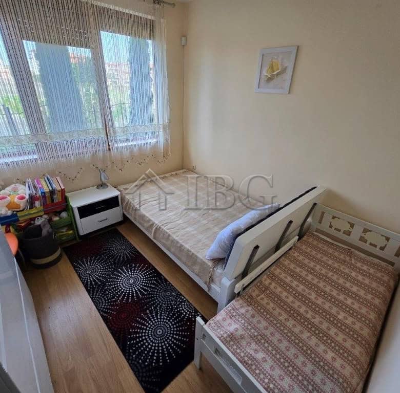 Bright bedroom with two beds and large window in Ravda apartment.
