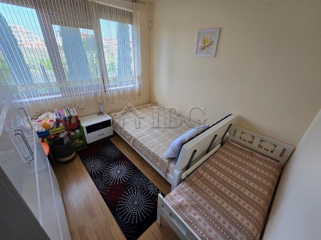 Bright bedroom with two beds and large window in Ravda apartment.