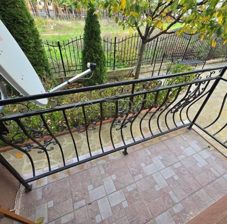 Balcony with decorative black metal railing overlooking a lush garden in Ravda, Bulgaria.