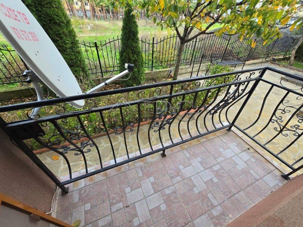 Balcony with decorative black metal railing overlooking a lush garden in Ravda, Bulgaria.