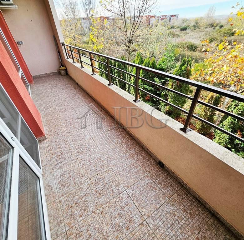 Balcony view of lush greenery and trees from a sunny beach apartment.
