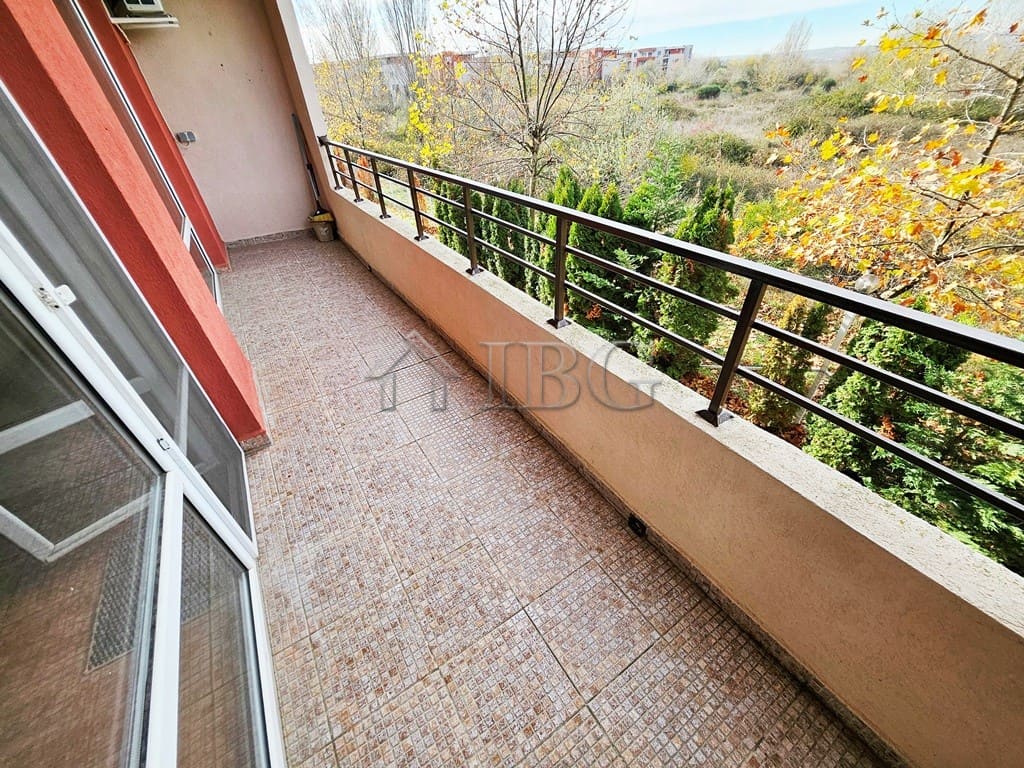 Balcony view of lush greenery and trees from a sunny beach apartment.