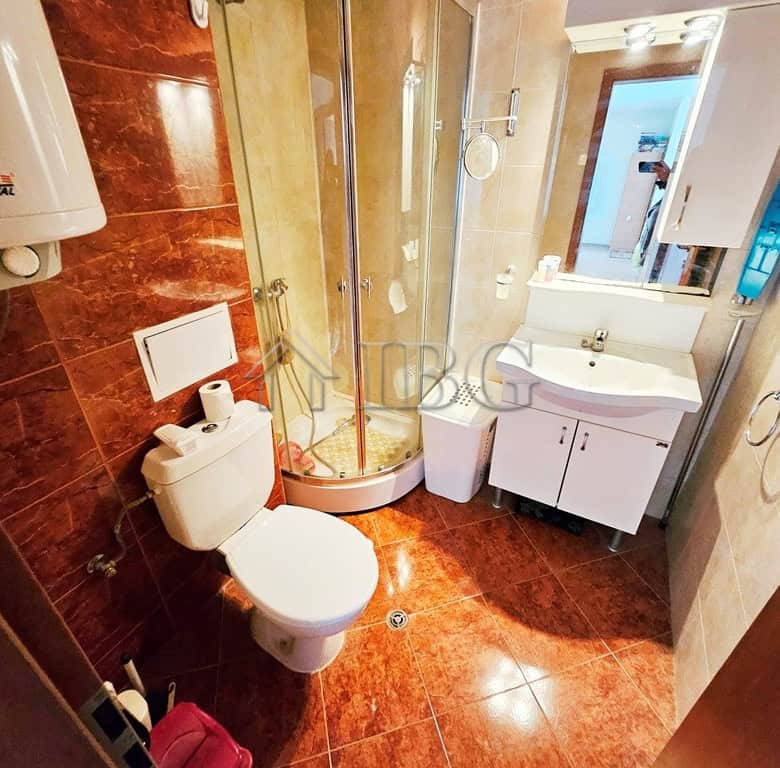 Bright bathroom with shower, toilet, and sink in Sunny Beach apartment.