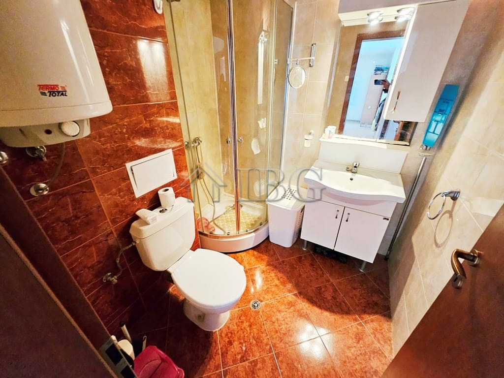 Bright bathroom with shower, toilet, and sink in Sunny Beach apartment.