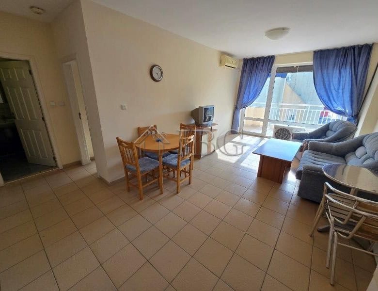 Bright living room with pool view, blue curtains, and balcony in Sunny Beach apartment.