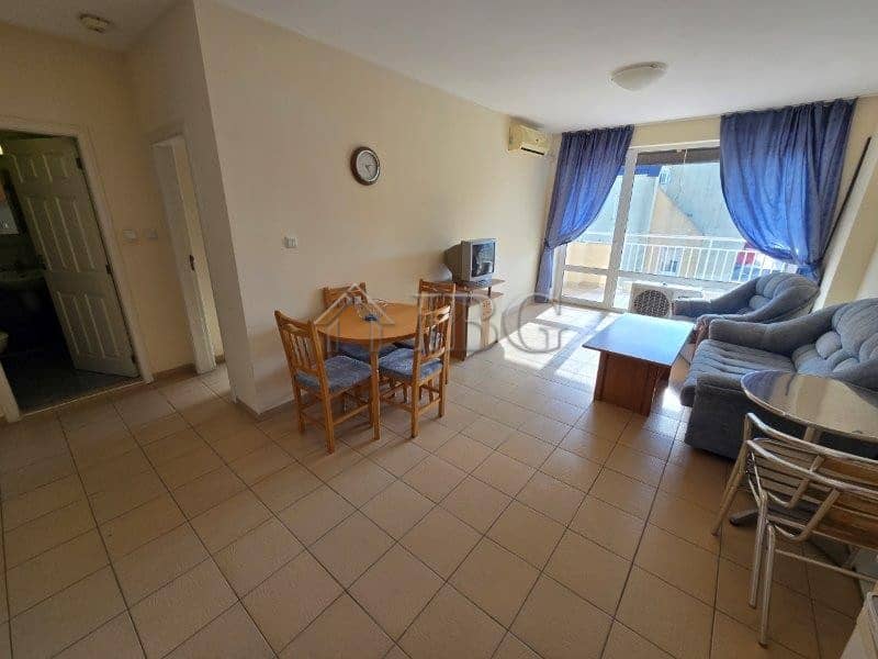 Bright living room with pool view, blue curtains, and balcony in Sunny Beach apartment.
