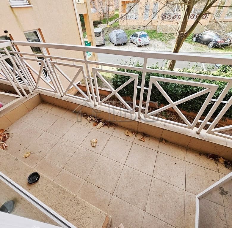 Balcony overlooking a quiet street with parked cars and greenery, perfect for relaxing outdoor momen.