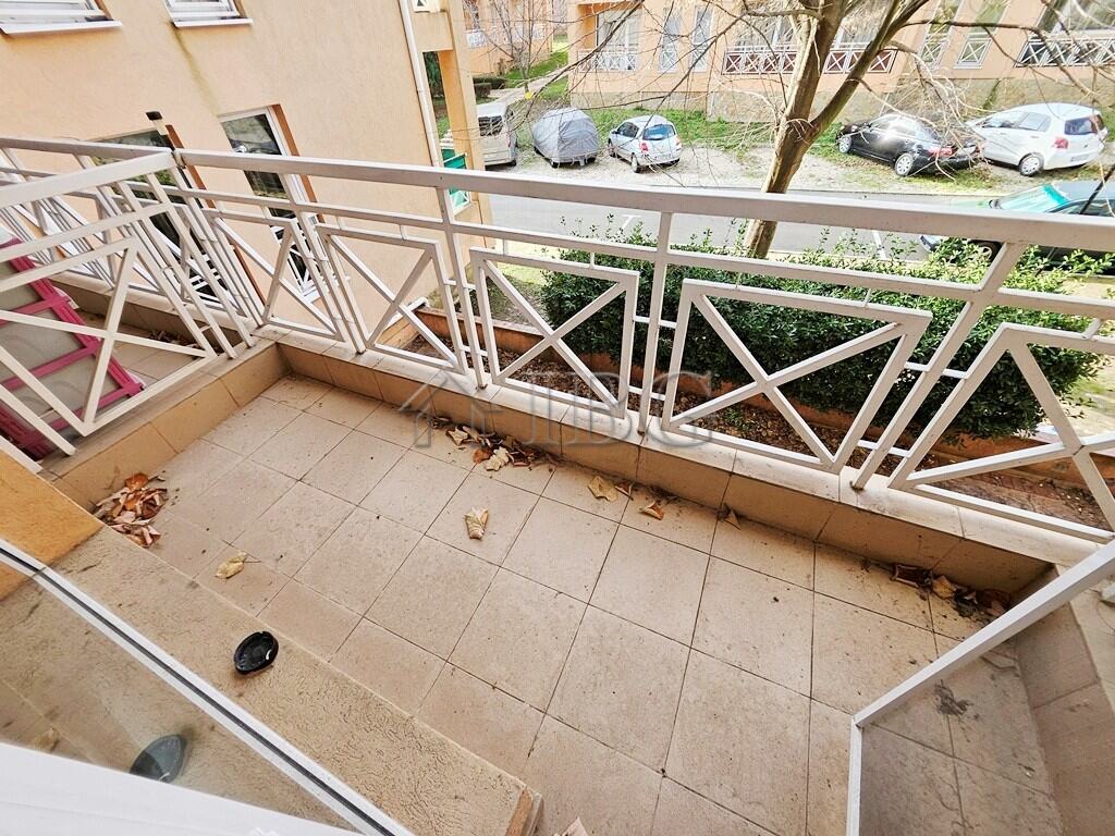 Balcony overlooking a quiet street with parked cars and greenery, perfect for relaxing outdoor momen.